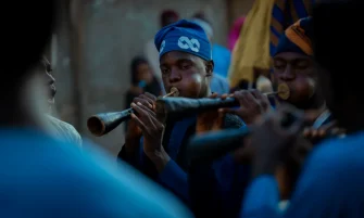 Group of musicians in traditional attire playing wind instruments during a cultural festival outdoors