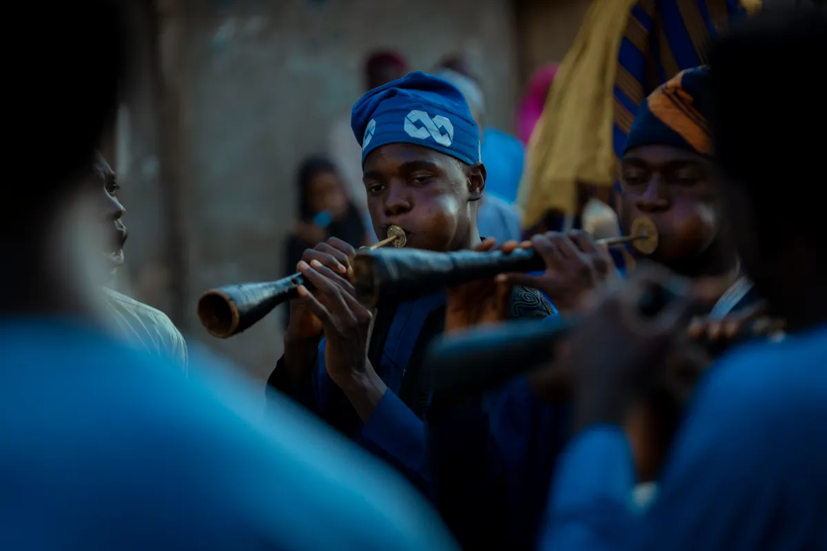 Group of musicians in traditional attire playing wind instruments during a cultural festival outdoors
