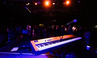 A vibrant nightclub scene with a keyboard and microphone on stage, ready for a live performance