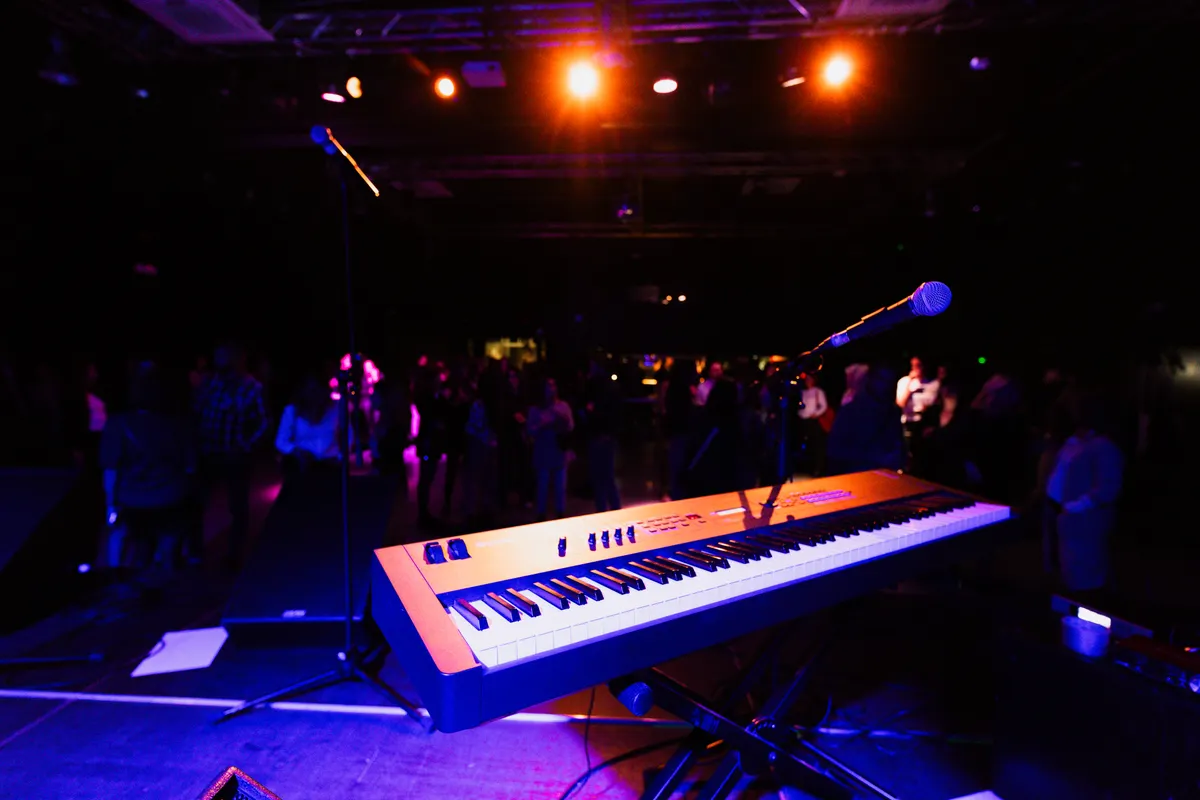 A vibrant nightclub scene with a keyboard and microphone on stage, ready for a live performance